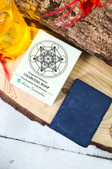 Handcrafted chocolate coffee cold process soap bar by Almitra Sustainable displayed with eco-friendly packaging on a wooden slab with natural flowers and oil bottle, natural detox soap for glowing skin made using traditional cold process method.