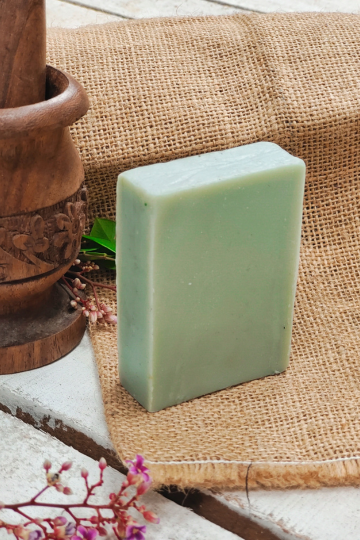 Green rectangular herbal soap bar handcrafted by Almitra Sustainables, displayed on rustic jute fabric with wooden mortar and dried floral accents – cold process, all-natural, and zero-waste soap.
