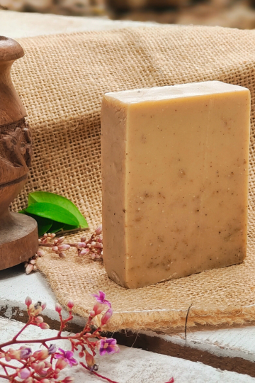 Close-up of a handmade rosemary cold process soap bar standing upright on burlap with natural decor, highlighting its herbal flecks and artisanal finish.