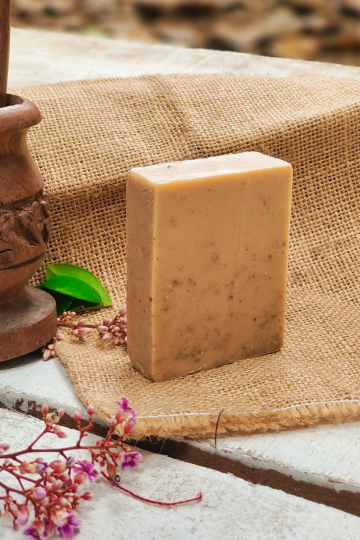 A rectangular bar of handcrafted rosemary cold process soap from Almitra Sustainables, placed on rustic burlap cloth with floral accents, showcasing its natural texture and earthy tones.