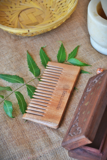 Natural neem wood comb with wide teeth for curly and thick hair, handcrafted by Almitra Sustainables. Pictured on jute fabric with neem leaves and rustic elements, showcasing its eco-friendly and Ayurvedic appeal.