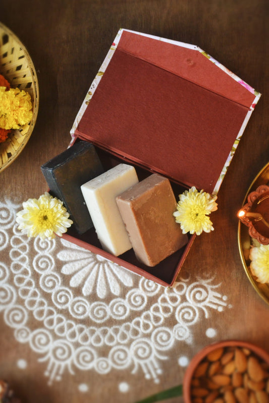 Eco-friendly festive gift box with three handcrafted natural soaps in sustainable packaging by Almitra Sustainables, placed on traditional rangoli with marigold flowers and diya — perfect for sustainable festive gifting.