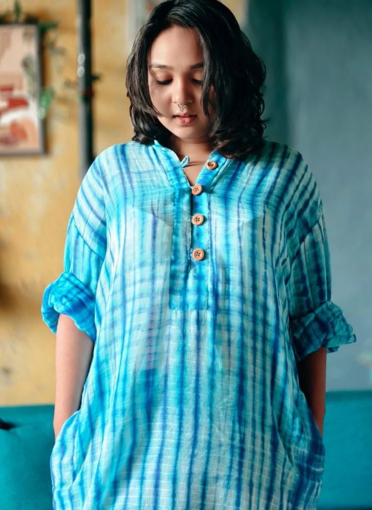 Woman wearing a blue tie-dye shirt in an indoor setting