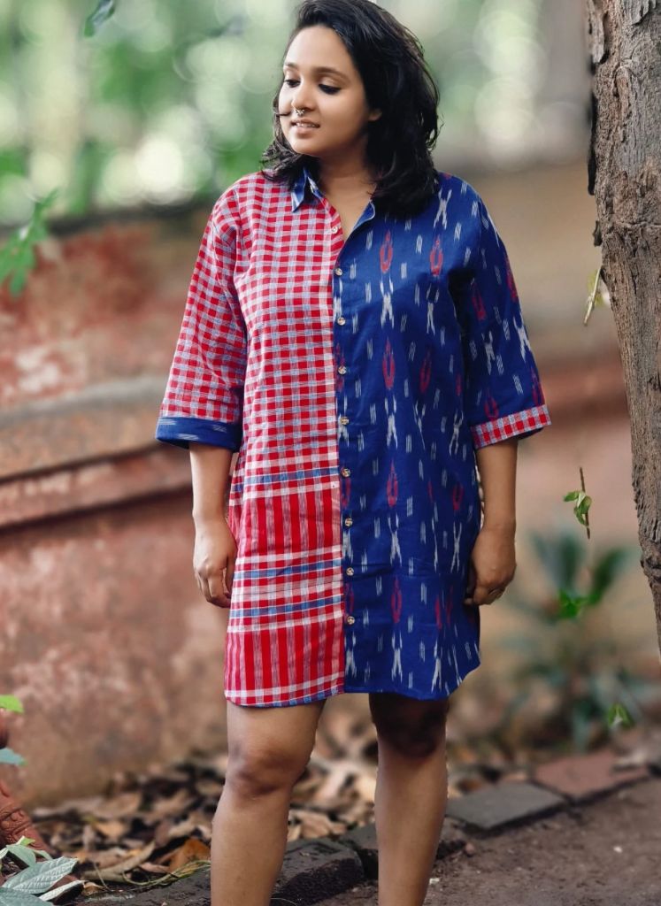 Woman wearing a red and blue checkered dress with a patterned design, standing outdoors.