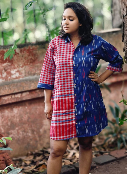 Woman wearing a red and blue checkered dress with a patterned blue shirt outdoors.