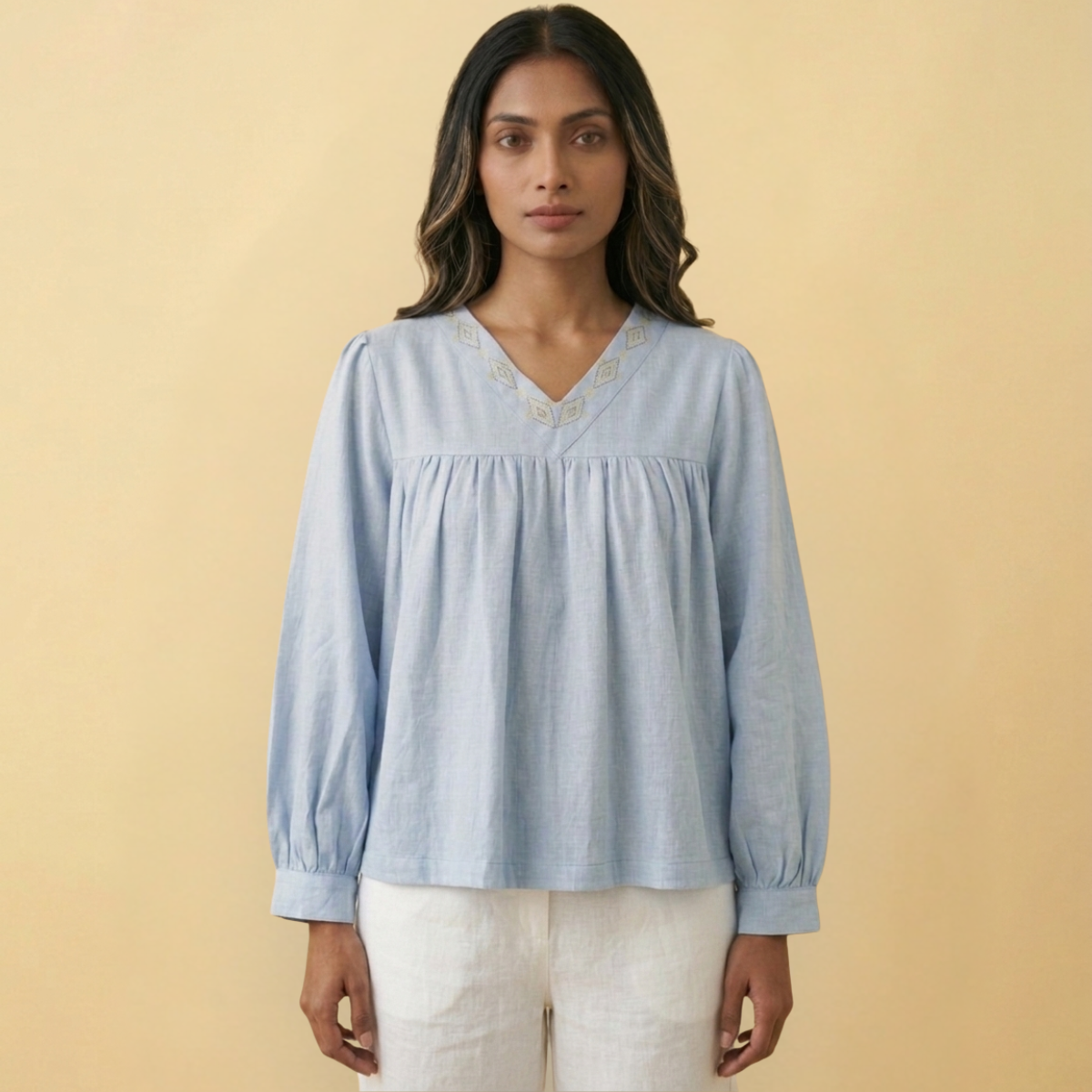 Woman wearing a light blue top with fish detailing on a beige background