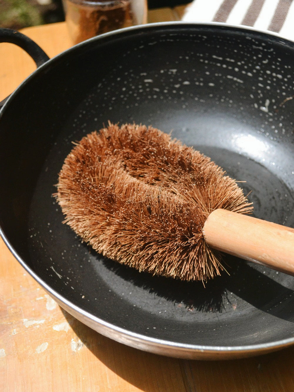 Sustainable pot cleaning brush with long wooden handle and natural coconut bristles for deep scrubbing.