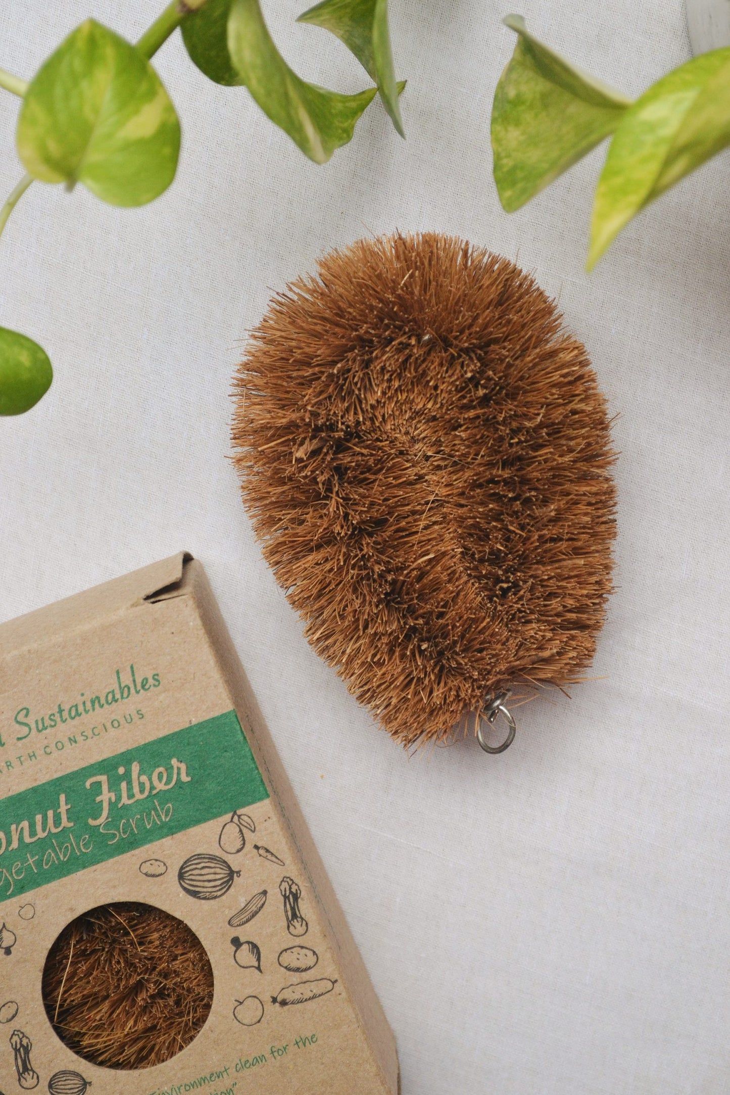 “Eco-friendly vegetable scrub made from natural coconut coir, placed on a rustic kitchen surface. The biodegradable scrub pad is designed for cleaning fruits, vegetables, and utensils, offering a sustainable alternative to synthetic scrubbers. Ideal for zero-waste, plastic-free kitchens.”