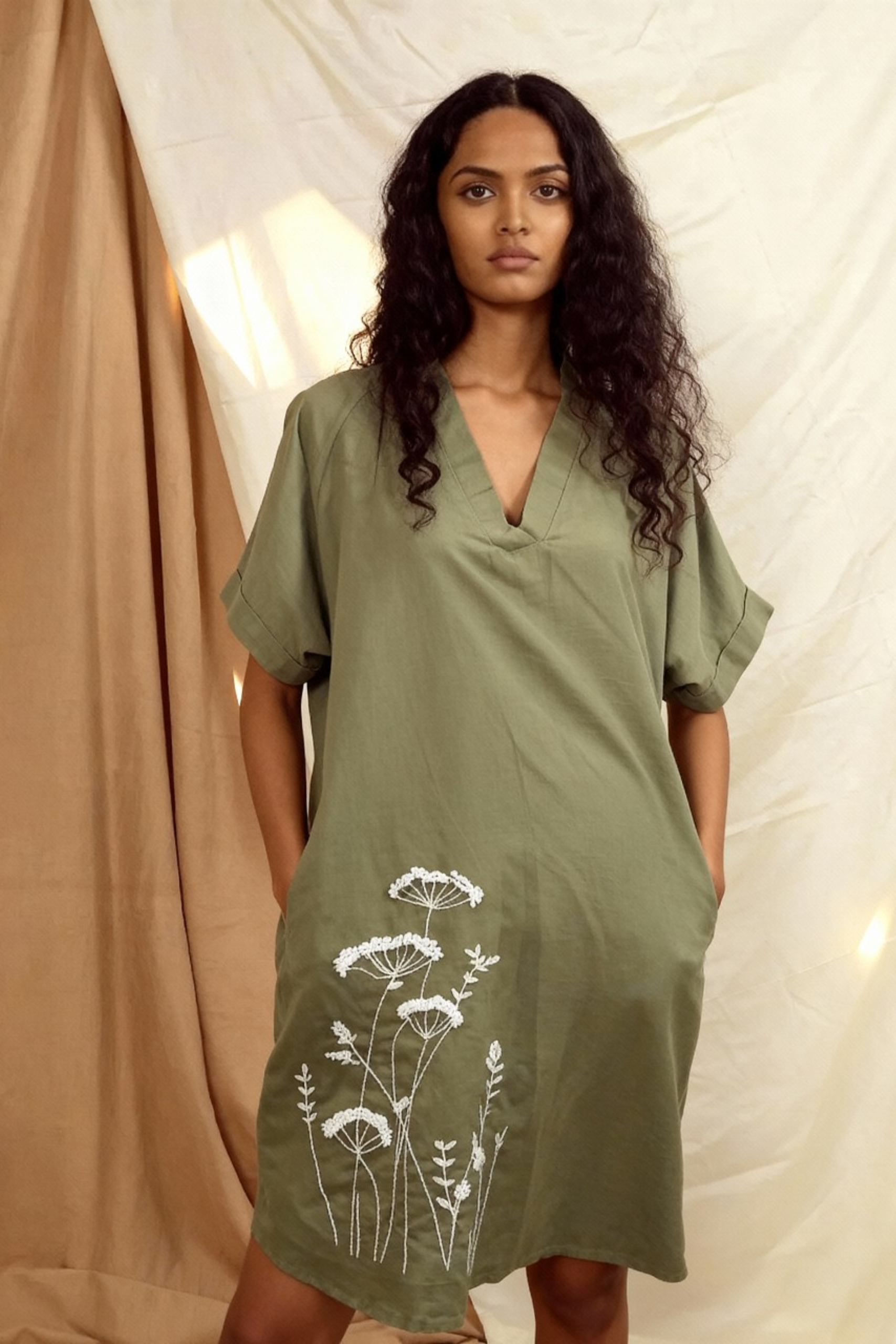 Woman wearing a green dress with white floral patterns against a neutral background