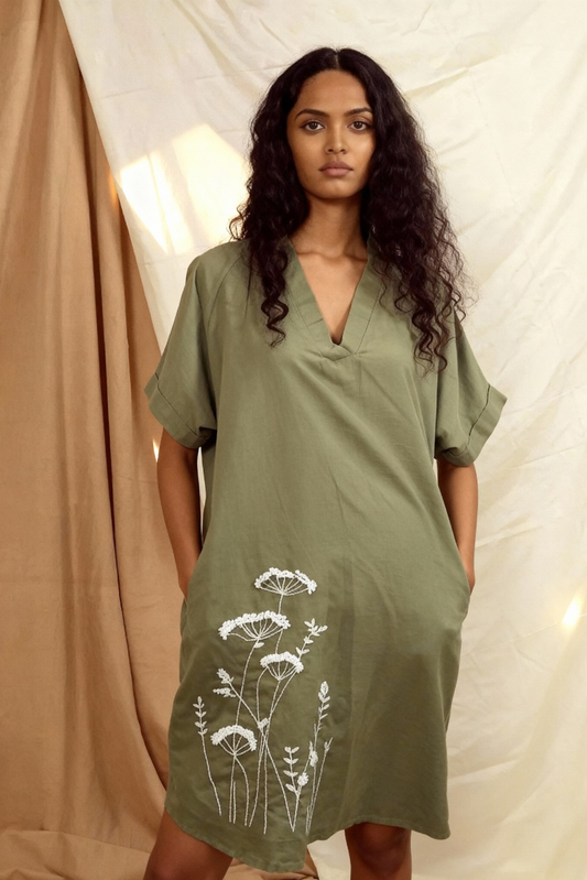 Woman wearing a green dress with white floral patterns against a neutral background