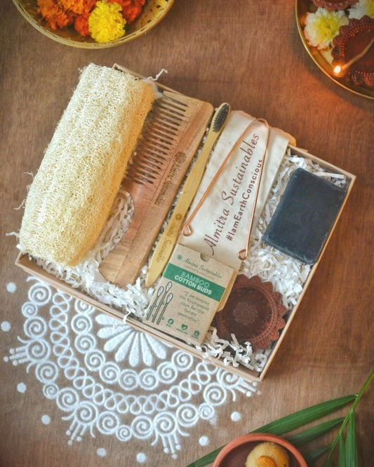 Eco-friendly self-care gift hamper by Almitra Sustainables featuring bamboo toothbrush, natural soap, wooden comb, loofah, bamboo cotton buds, and reusable pouch in sustainable packaging with festive rangoli, marigold flowers, and clay diyas — ideal zero-waste Diwali gift.